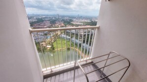 A balcony with a metal railing overlooking a cityscape with buildings and a river. - Good Studio Near Binus At Pacific Garden Apartment (Tangerang)