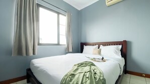 A bedroom with a single bed, a window with curtains, and a ceiling fan. - Spacious And Comfy 3Br At Puri Garden Apartment (Jakarta)