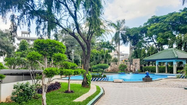 A landscaped area with a swimming pool, surrounded by trees and a gazebo. - Spacious And Comfy 3Br At Puri Garden Apartment (Jakarta)