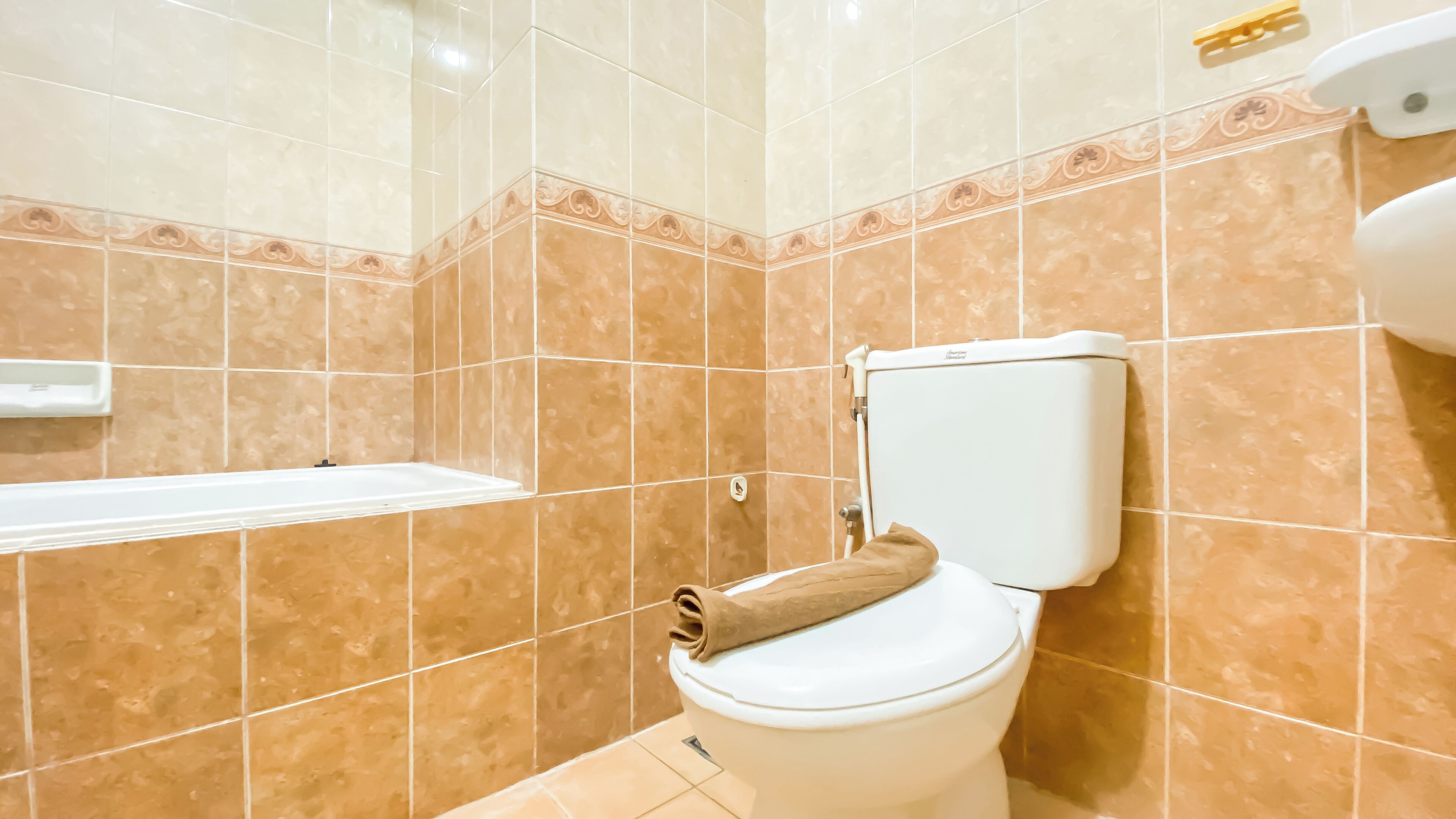 A bathroom with a toilet, a bathtub, and tiled walls.