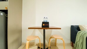 A small room with a table, two chairs, a water bottle, and a travel bag. - Cozy And Best Location 1Br Gold Coast Apartment (Jakarta)
