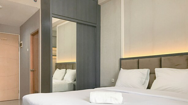 Une chambre d’hôtel avec un grand lit, un miroir et une porte.