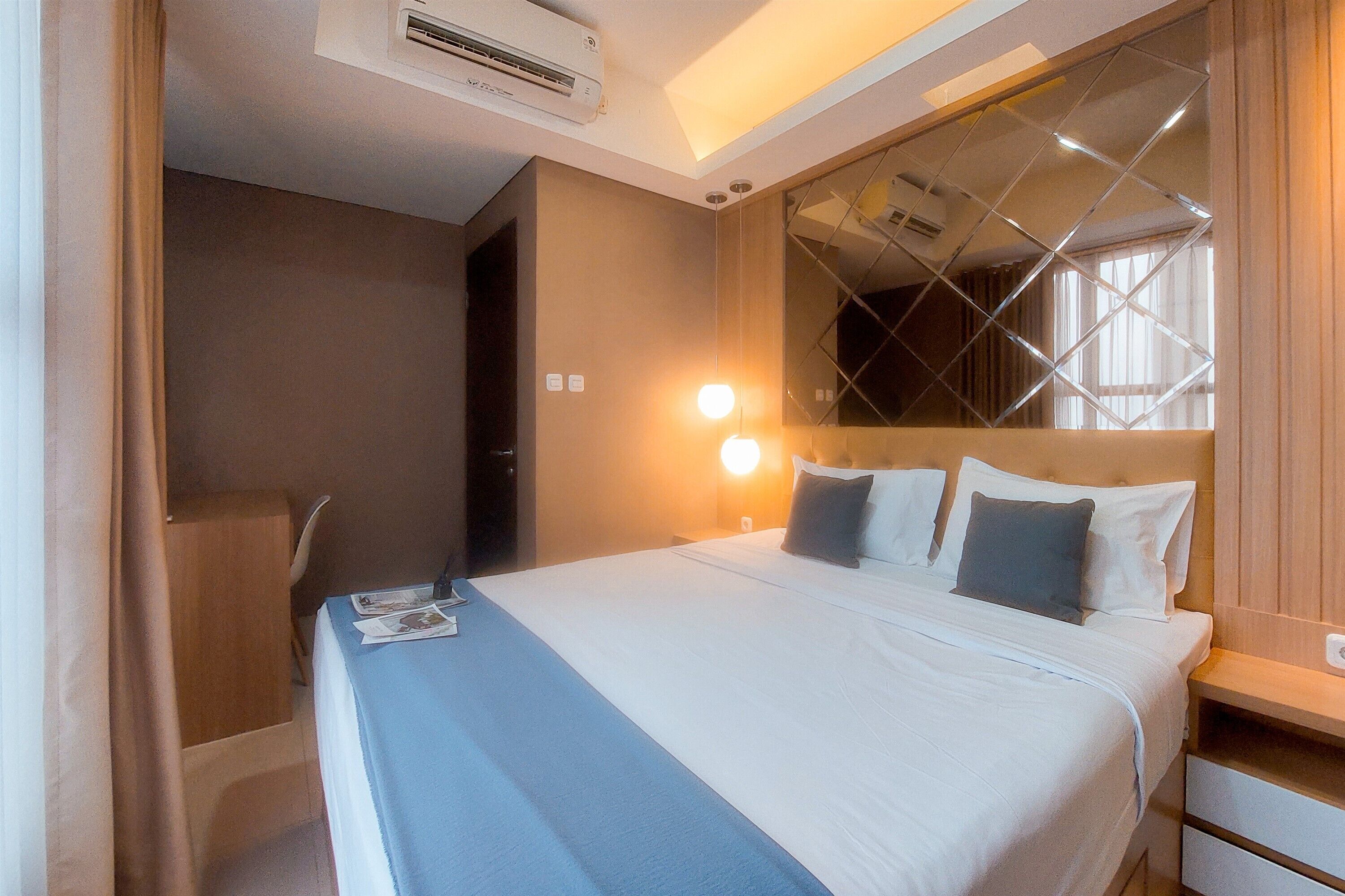 Una habitación de hotel con cama, mesita de noche y espejo de diseño geométrico.