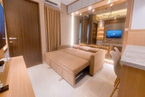 Ein modernes Schlafzimmer mit Schlafsofa, Fernseher und Schreibtisch mit Stuhl.
