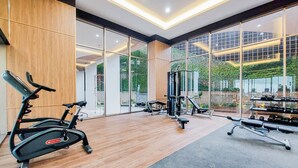 A modern gym with cardio equipment, weight machines, and dumbbells. - Cozy And Elegant 2Br Apartment At Transpark Bintaro (South Tangerang)