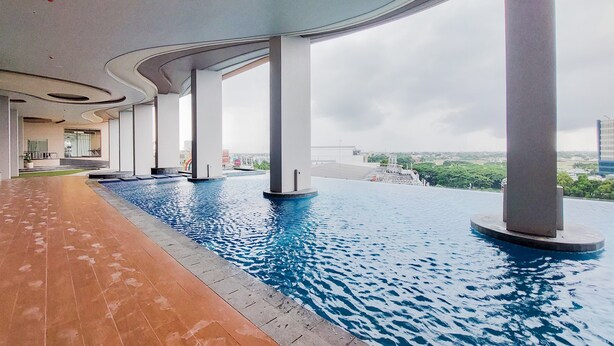 A modern indoor pool with a curved ceiling and large pillars, surrounded by a tiled walkway. - Cozy And Elegant 2Br Apartment At Transpark Bintaro (South Tangerang)