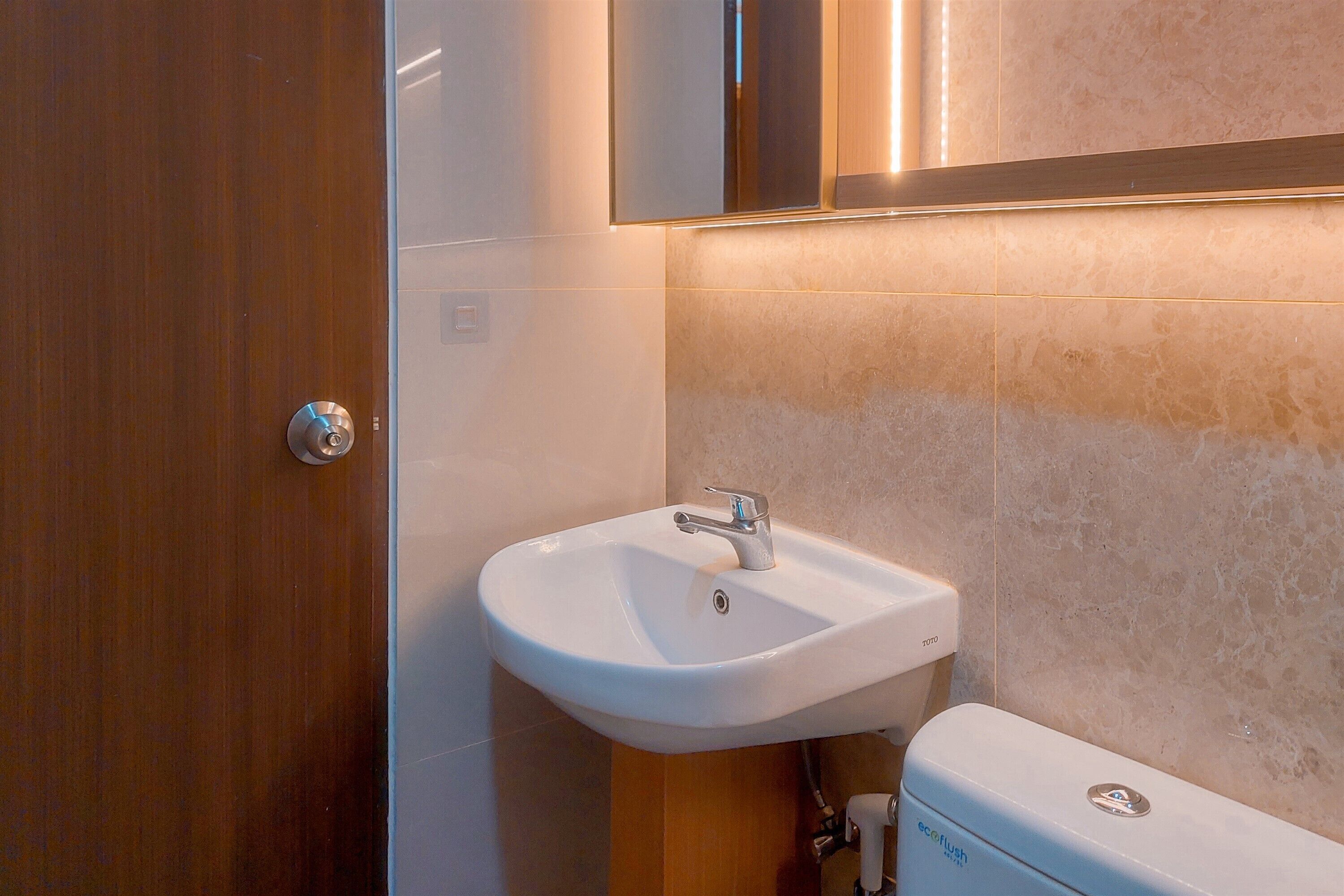 A bathroom with a white sink, a wooden door, and a toilet.