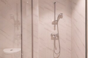 A glass-enclosed shower with a handheld showerhead and a fixed overhead faucet. - Elegant 1Br Apartment At Branz Bsd City (Pagedangan)