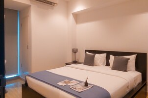 A neatly made bed with a blue bedspread, a bedside lamp, and a nightstand.