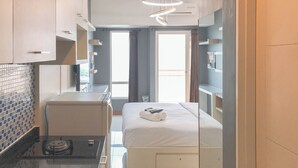 Una habitación de hotel moderna con una cama, un escritorio pequeño, un espejo y una ventana con cortinas.