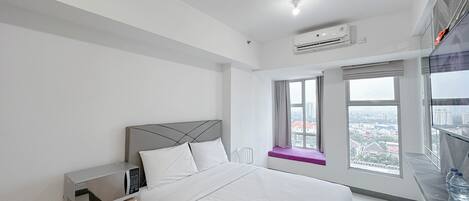 A modern bedroom with a bed, a nightstand, a window with a view, and an air conditioning unit.