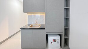 A compact kitchen with a built-in sink, a small refrigerator, and a cabinet with a marble backsplash. - Studio (No Kitchen) With City Light View Benson Supermall Mansion Apartment (Surabaya)