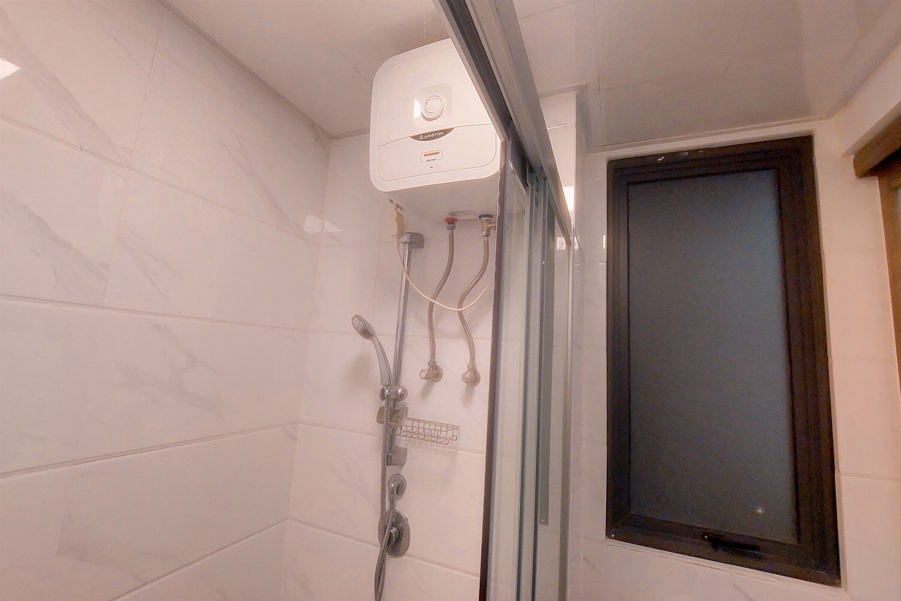 Une douche dotée d’un panneau de commande, d’une porte en verre et d’un mur carrelé.