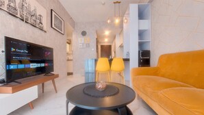 Una sala de estar moderna con un televisor de pantalla plana, una mesa de centro redonda negra, un sofá amarillo y un comedor con sillas amarillas.