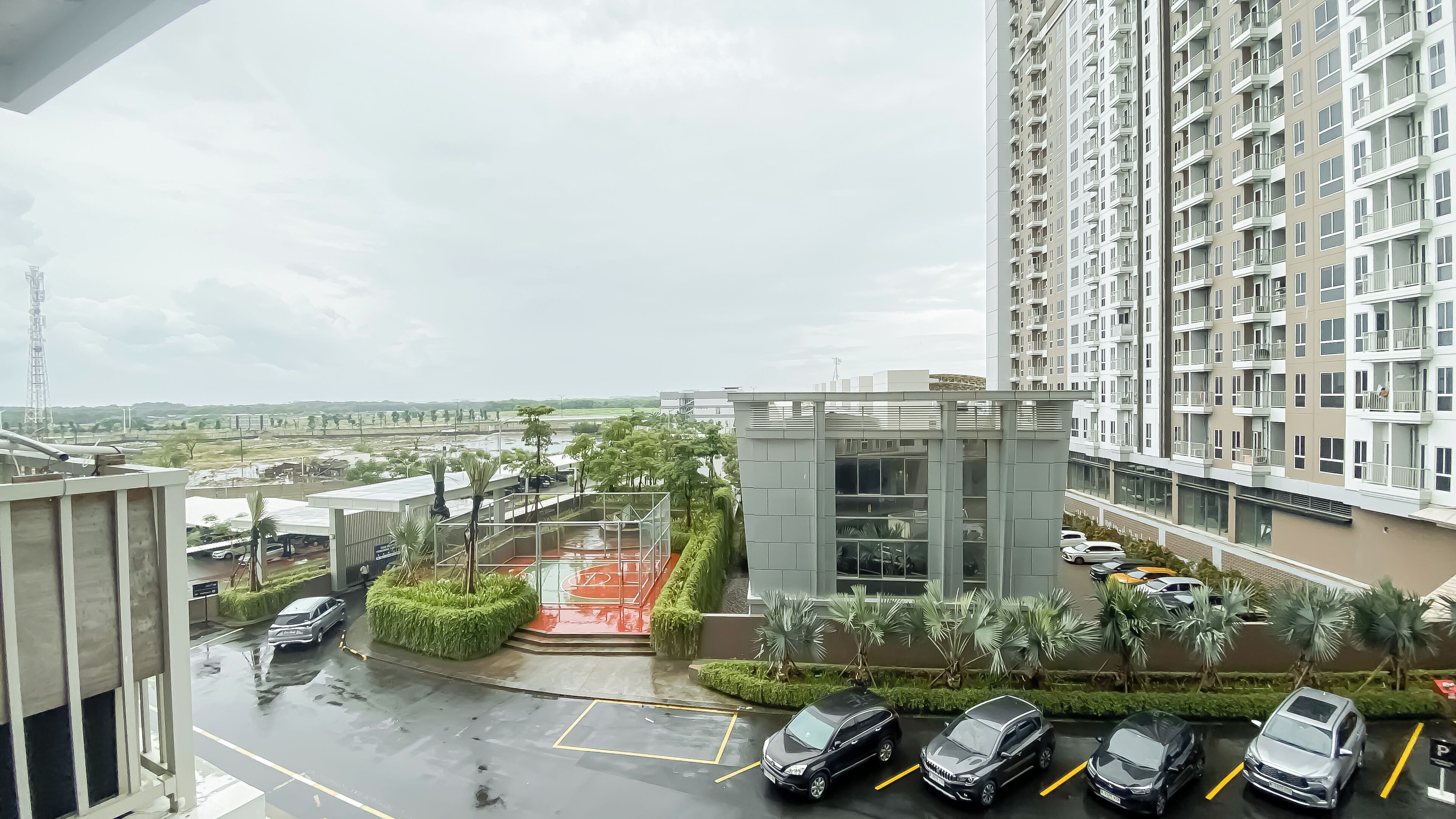Un immeuble résidentiel moderne doté d’un espace de stationnement, d’un petit jardin et offrant une vue sur un paysage lointain.