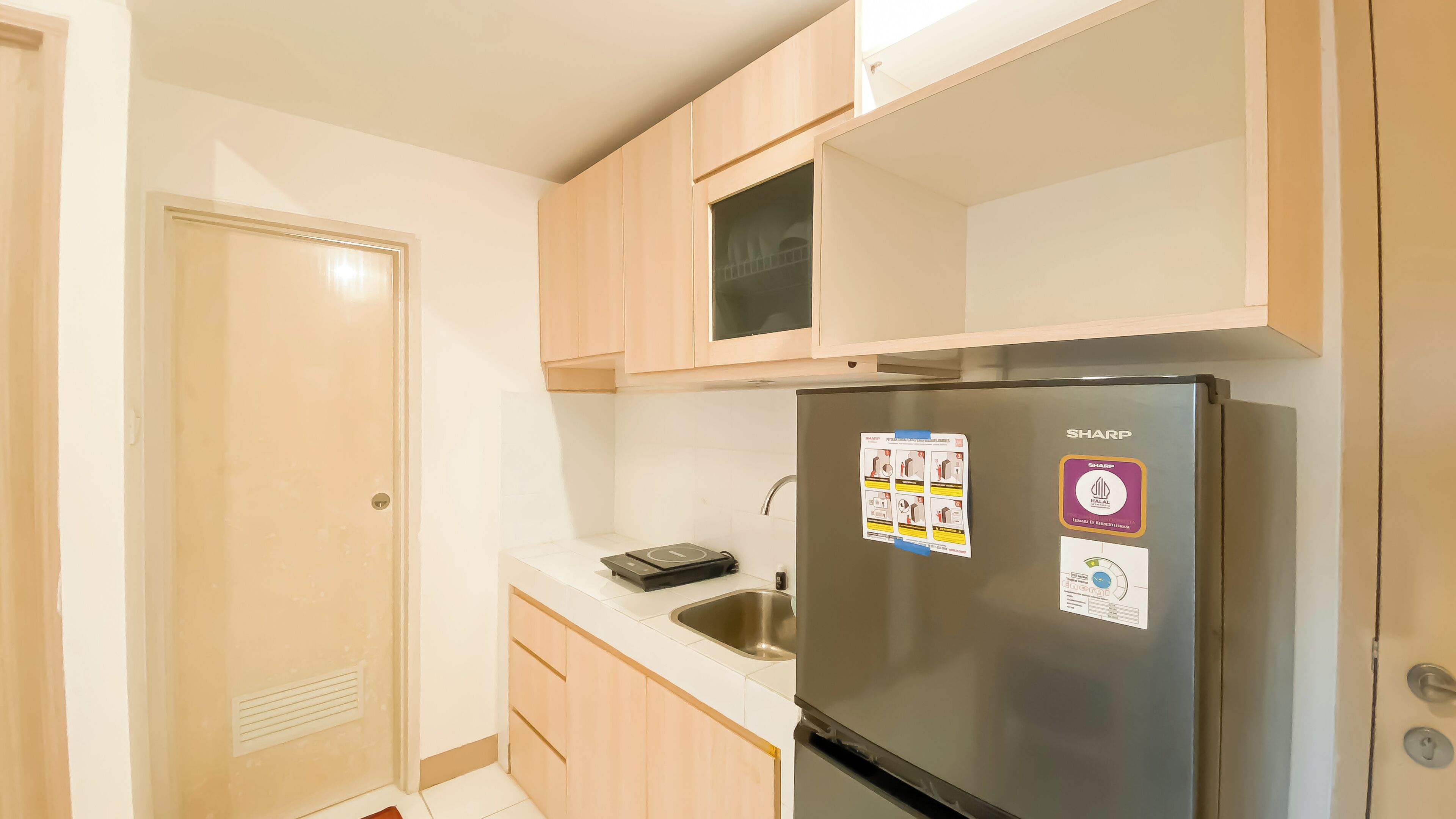 Una cucina compatta con frigorifero in acciaio inox, lavello e mobili in legno.