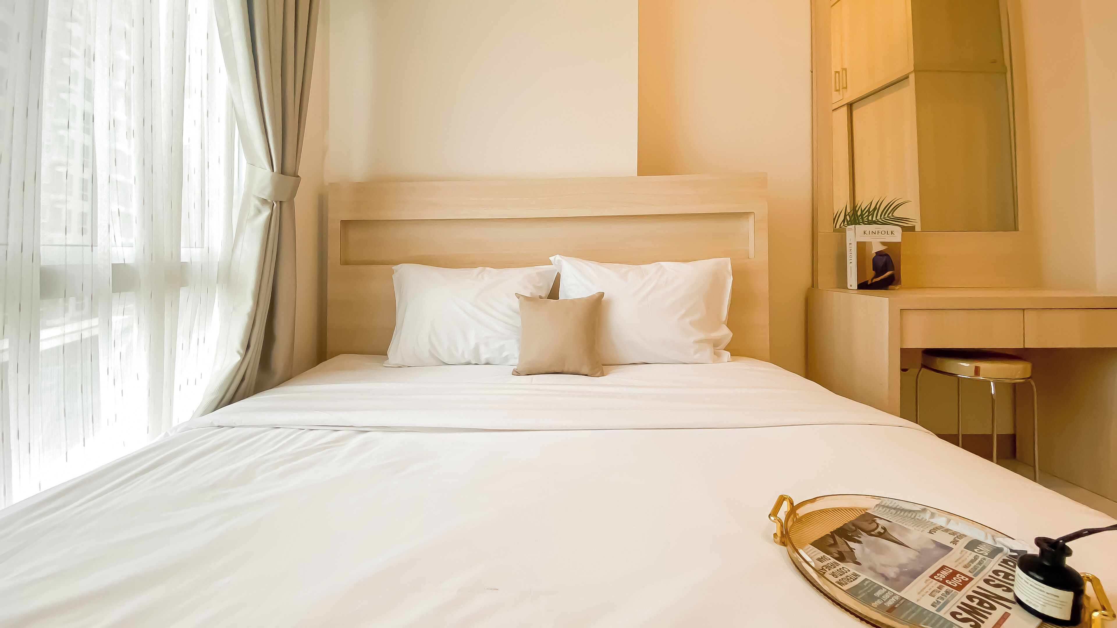 Ein Hotelzimmer mit Bett, Nachttisch, Spiegel und einem Fenster mit Vorhängen.