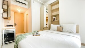 A hotel room with a bed, a desk with a computer, a mirror, and a wardrobe. - Best Deal Studio At 23Rd Floor Tokyo Riverside Pik 2 Apartment (Teluknaga)