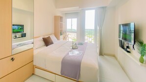 A hotel room with a large bed, a TV mounted on the wall, and a balcony with a view.