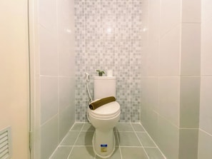 A small, modern bathroom with a toilet, a shower, and a tiled wall.
