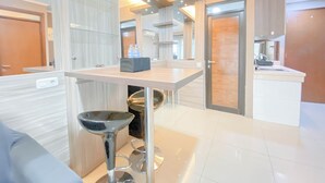 A modern kitchen with a central island, stainless steel appliances, and a glass partition. - The Modern Classic 2Br With Scenic View At Gateway Pasteur Apartment (Cimahi)