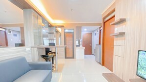 A modern hotel lobby with a blue sofa, a reception desk, and a TV screen. - The Modern Classic 2Br With Scenic View At Gateway Pasteur Apartment (Cimahi)
