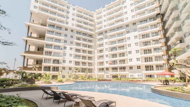 A modern multi-story residential building with a central swimming pool and outdoor seating area. - The Modern Classic 2Br With Scenic View At Gateway Pasteur Apartment (Cimahi)