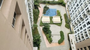 A rooftop garden with a swimming pool, seating areas, and a small bridge.