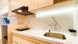 A modern kitchen with a marble countertop, stainless steel sink, and a built-in range hood.