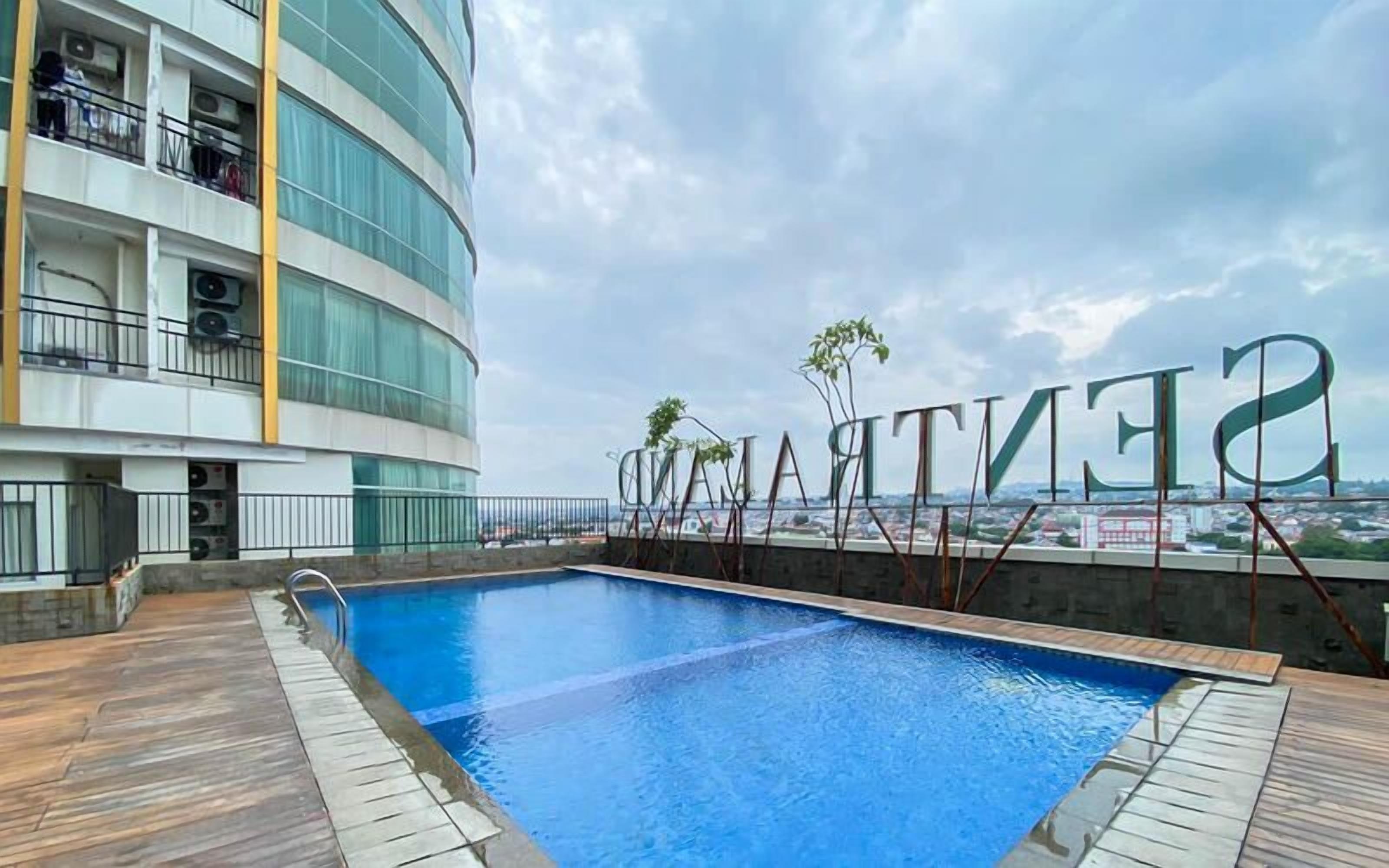 Una piscina en la azotea con vistas a un paisaje urbano y un edificio con balcones.