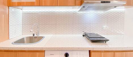 Una cocina con gabinetes de madera, un lavamanos de acero inoxidable, lavavajillas integrado y un microondas.