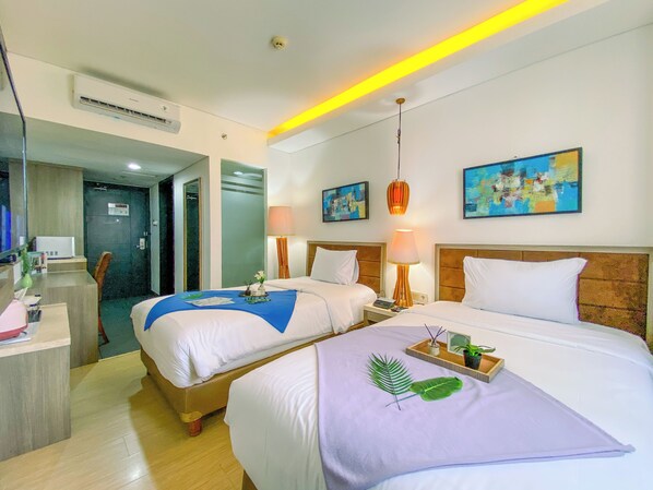 A hotel room with two beds, a desk, and a bathroom.