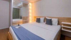 A hotel room with a bed, bedside tables, a mirror, and a sliding door leading to a bathroom. - Cozy And Simply 1Br Apartment Anwa Residence (South Tangerang)