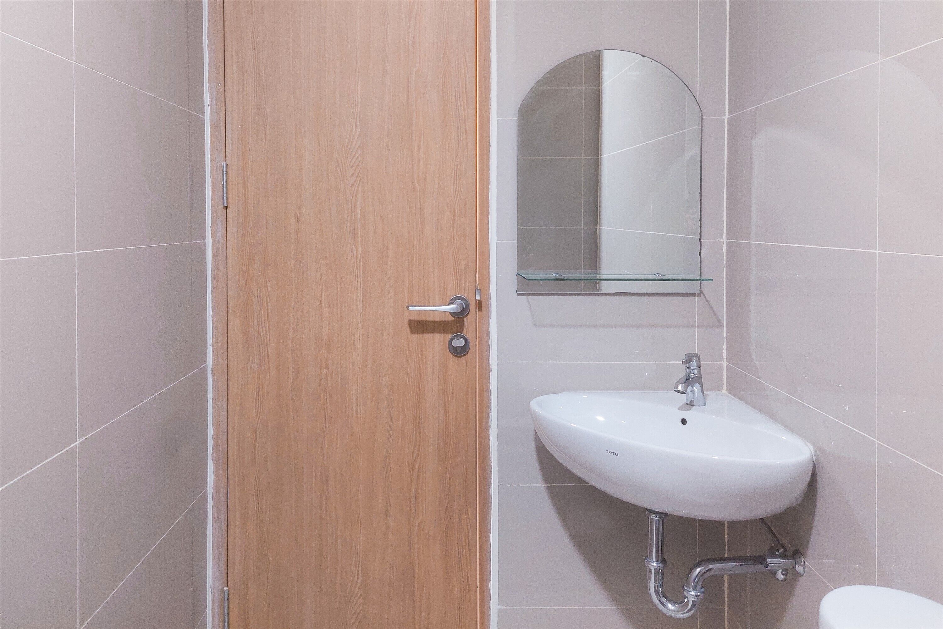 A bathroom with a wooden door, a white sink, and a mirror above it.