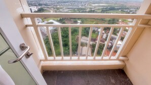 A balcony with a metal railing overlooking a cityscape with buildings and roads.