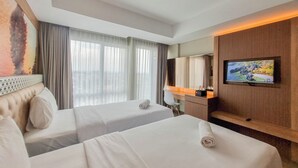 A hotel room with two beds, a desk, a television, and a large window with curtains. - Cozy Studio Apartment At Grand Mercure Yogyakarta (Yogyakarta)