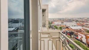 A balcony with a city view, including buildings and a street. - Cozy Studio Apartment At Grand Mercure Yogyakarta (Yogyakarta)