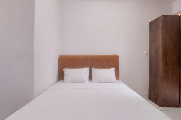 Simple, functional room with a single bed, wooden headboard, and wardrobe for storage.