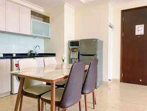 Enjoy meals at the dining table with four chairs, adjacent to a modern kitchen with microwave and stainless steel sink.