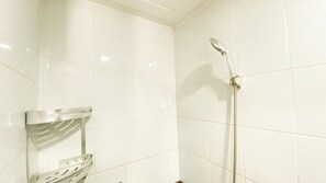 Bathroom features a shower with a handheld showerhead and a metal grab bar for added safety.