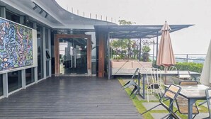An outdoor seating area with a wooden deck, metal chairs, and a table. - Cozy And Warm Studio Room At Uttara The Icon Apartment (Depok)