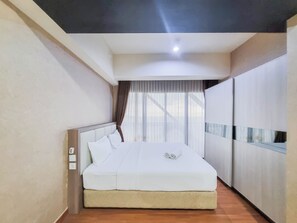 Une chambre d’hôtel moderne avec un grand lit, une armoire et une fenêtre agrémentée de rideaux légers.