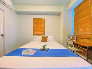 Une chambre d’hôtel avec un lit, une petite table avec un plateau et une chaise.