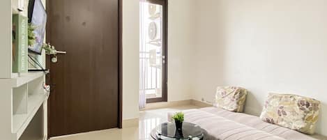 Una sala de estar moderna con un sofá, una mesa de centro de vidrio y una puerta que da a otra habitación.