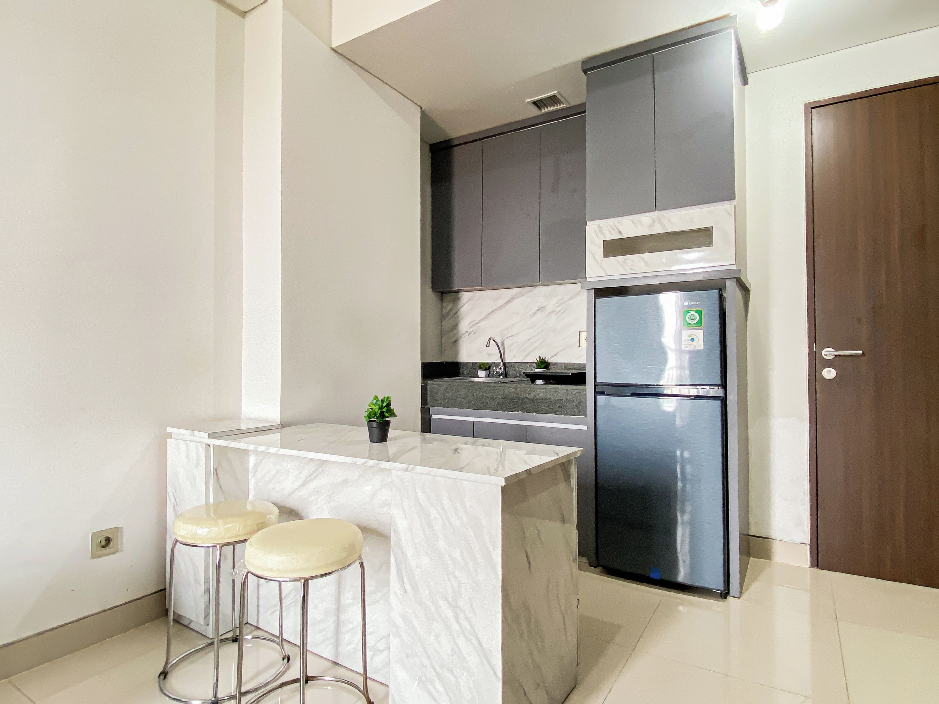 A modern kitchen with a marble countertop, stainless steel appliances, and two bar stools.