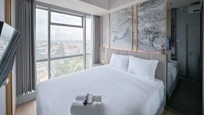 Habitación de hotel con una cama grande, televisión, vistas de la ciudad y un cuadro abstracto de gran tamaño en la pared.