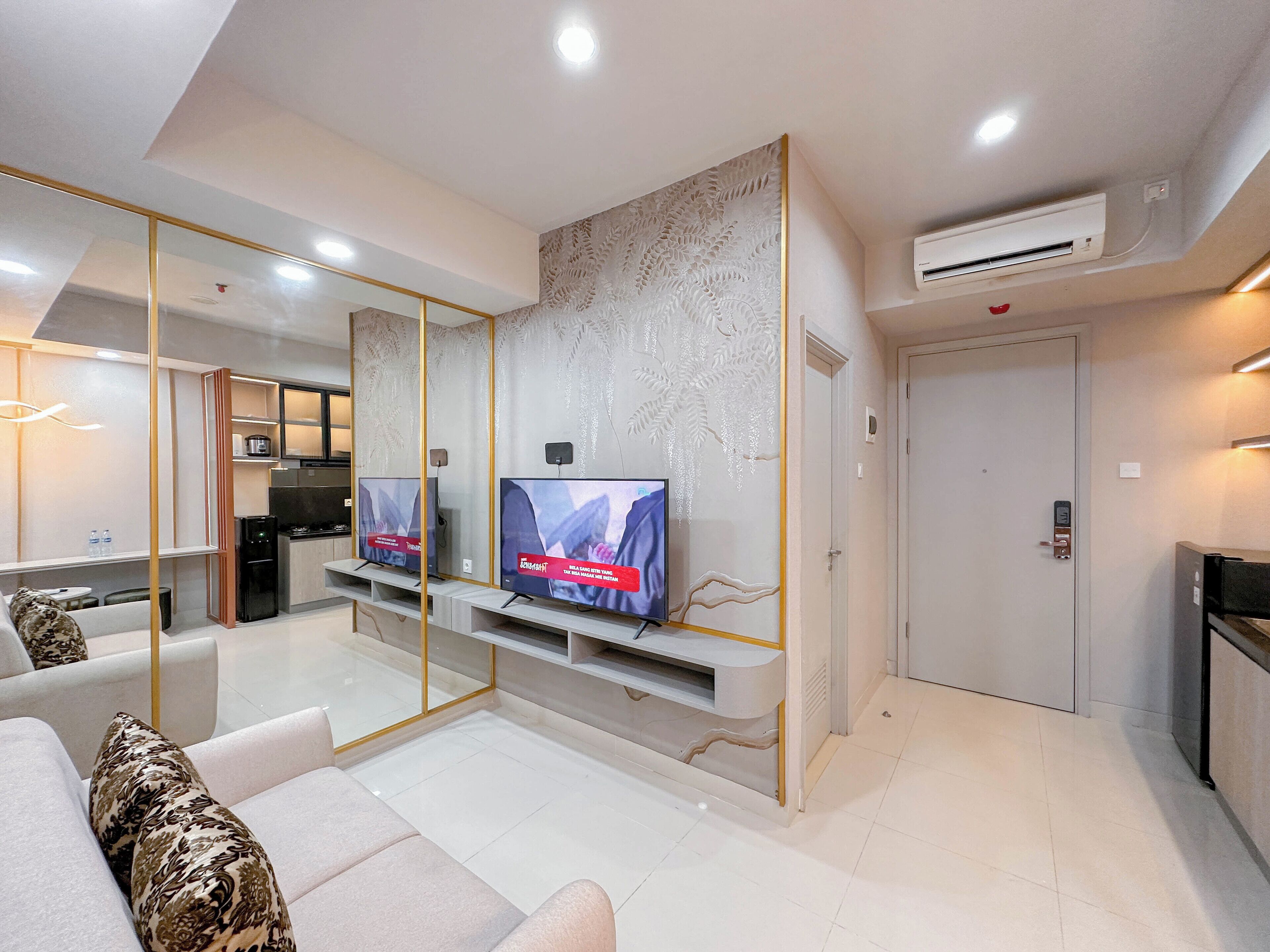 A modern living room with a flat-screen TV, a sofa, a coffee table, and a kitchen area in the background.