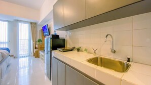 A modern kitchen with a stainless steel sink, white tiled backsplash, and a flat-screen TV mounted above the counter. - Serene Studio At 25Th Floor Apartment Tokyo Riverside Pik 2 (Teluknaga)
