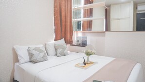 A neatly arranged bedroom with a bed, bedside table, and a mirror above the bed.