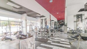 A gym with various exercise equipment, large windows, and a checkered floor. - The Chic 2Br Apartment At The Edge Bandung (Cimahi)